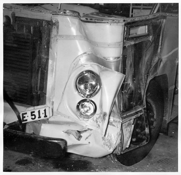 Schwarzes und weißes Foto eines stark beschädigten Autos mit sichtbarer Rost und Dellen, Frontseite zeigt auf den Betrachter.