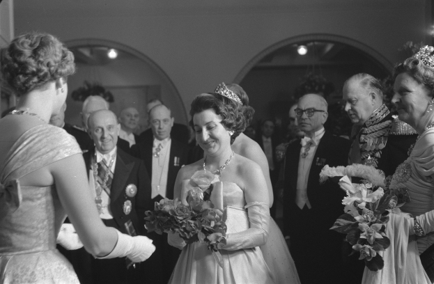 Schwarzes und weißes Foto von Queen Elizabeth II. und Prinz Philip, Duke of Edinburgh, an ihrem Hochzeitstag in Kronen und mit Blumensträußen, umgeben von einer Gruppe von Menschen.