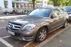 Ein Mercedes-Benz GLK 350 CDI BlueEfficiency Avantgarde, der auf einer Straße mit Bäumen und Gebäuden mit Fenstern im Hintergrund fährt.