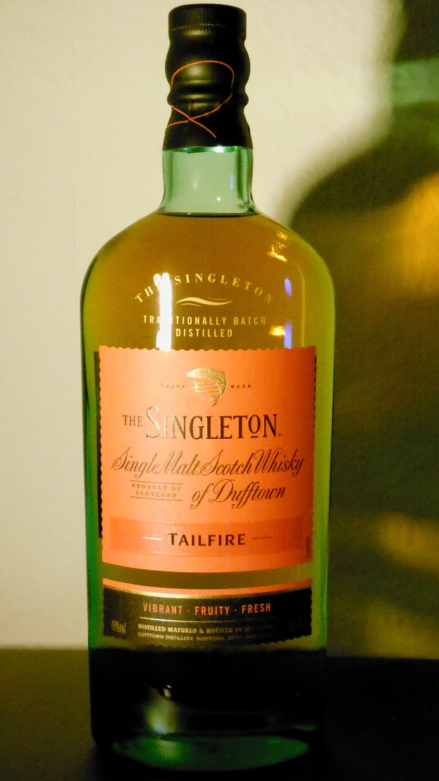 Tiefe Bernsteinflasche Singleton of Dufftown Tailfire Single Malt Scotch Whisky mit einem schwarzen Etikett, das ein Löwen- und Schlosswappen zeigt, auf einem Tisch.