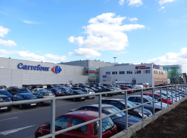 Großes Autohaus mit parkenden Fahrzeugen vor einem urbanen Hintergrund