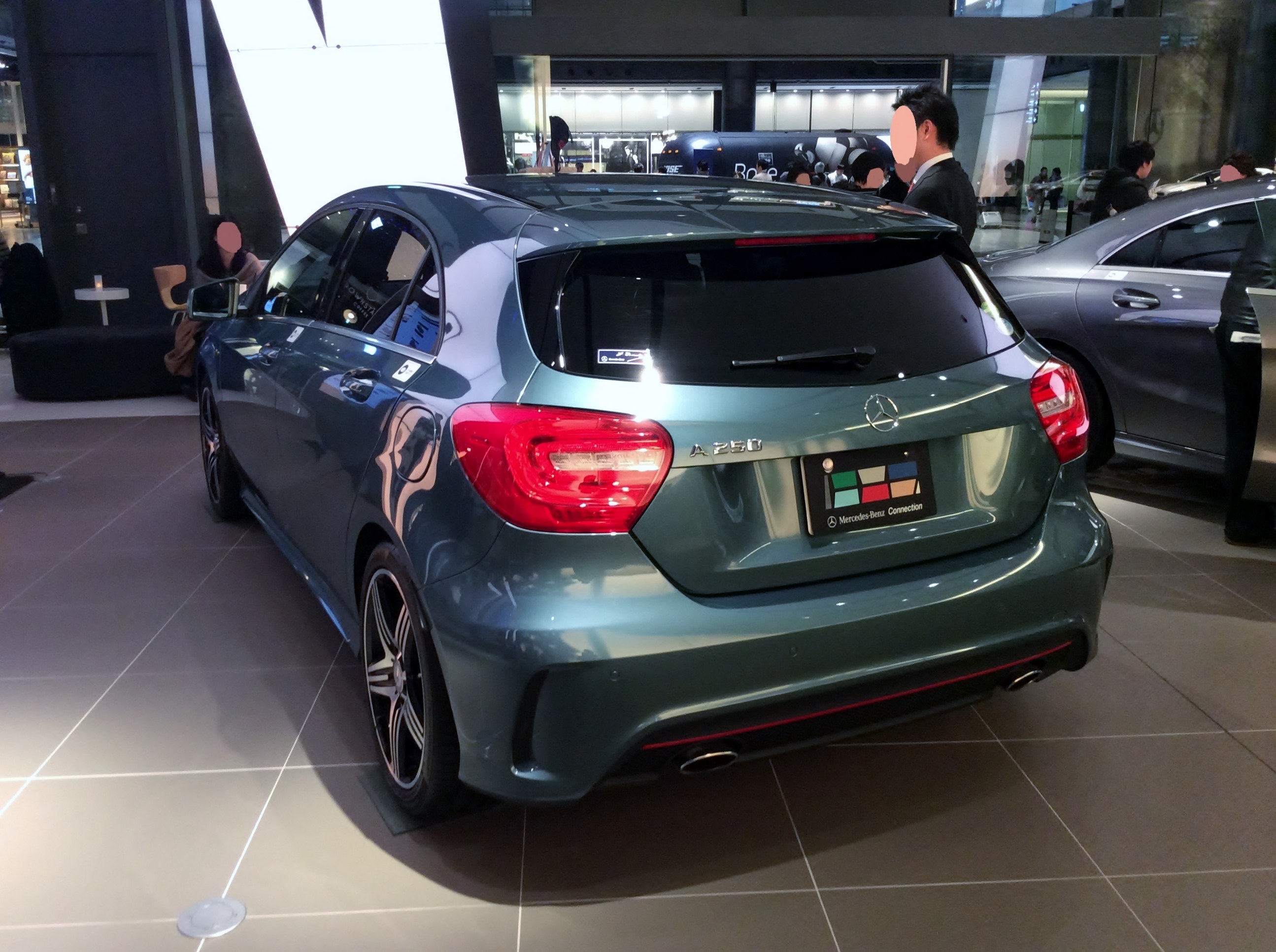 Mercedes-Benz A-Klasse Limousine mit glänzender schwarzer Lackierung, Chromakzenten und Aluminiumrädern, die auf der IAA in Frankfurt umgeben von Menschen gezeigt wird.