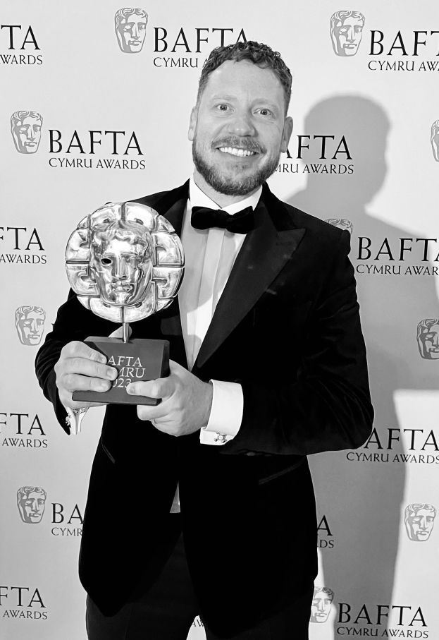 Ein Mann in einem Smoking, der eine BAFTA-Trophäe hält, vor einer Tafel mit der Aufschrift "BAFTA Awards 2018".