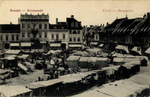 Schwarzes und weißes Foto eines vollen Marktes in Kronstadt, Deutschland mit Menschen, Zelten und Gebäuden im Hintergrund.