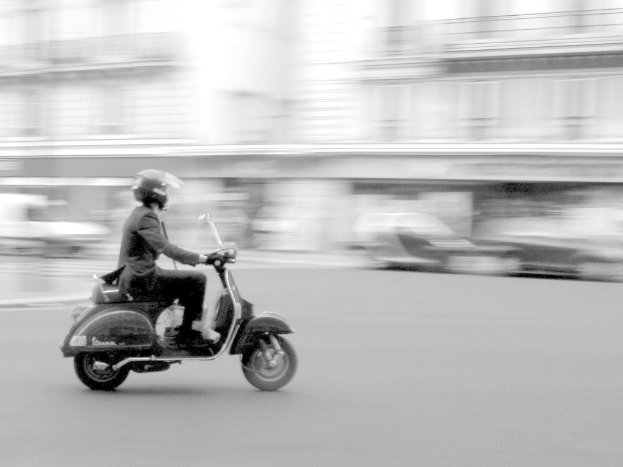 Eine Person auf einem Roller auf der Straße.