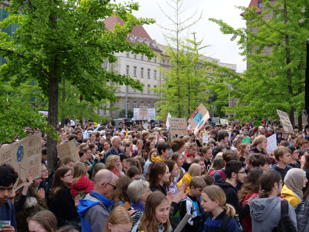 Eine große Menschenmenge protestiert vor einem Gebäude in Berlin und hält Schilder