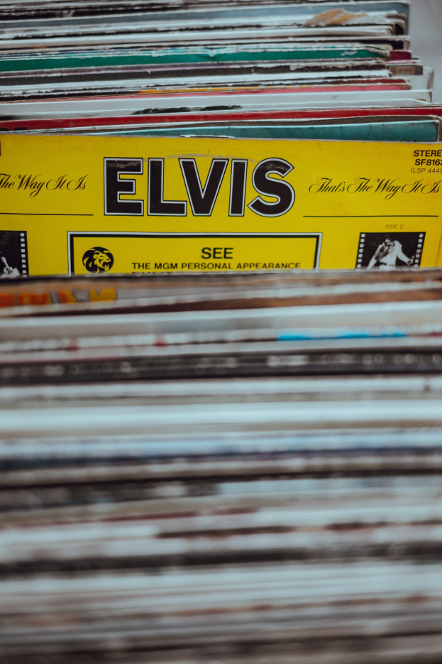 Ein ordentlicher Stapel Elvis Presley-Platten auf einem Tisch, mit sichtbaren Titeln und einem unscharfen Hintergrund.