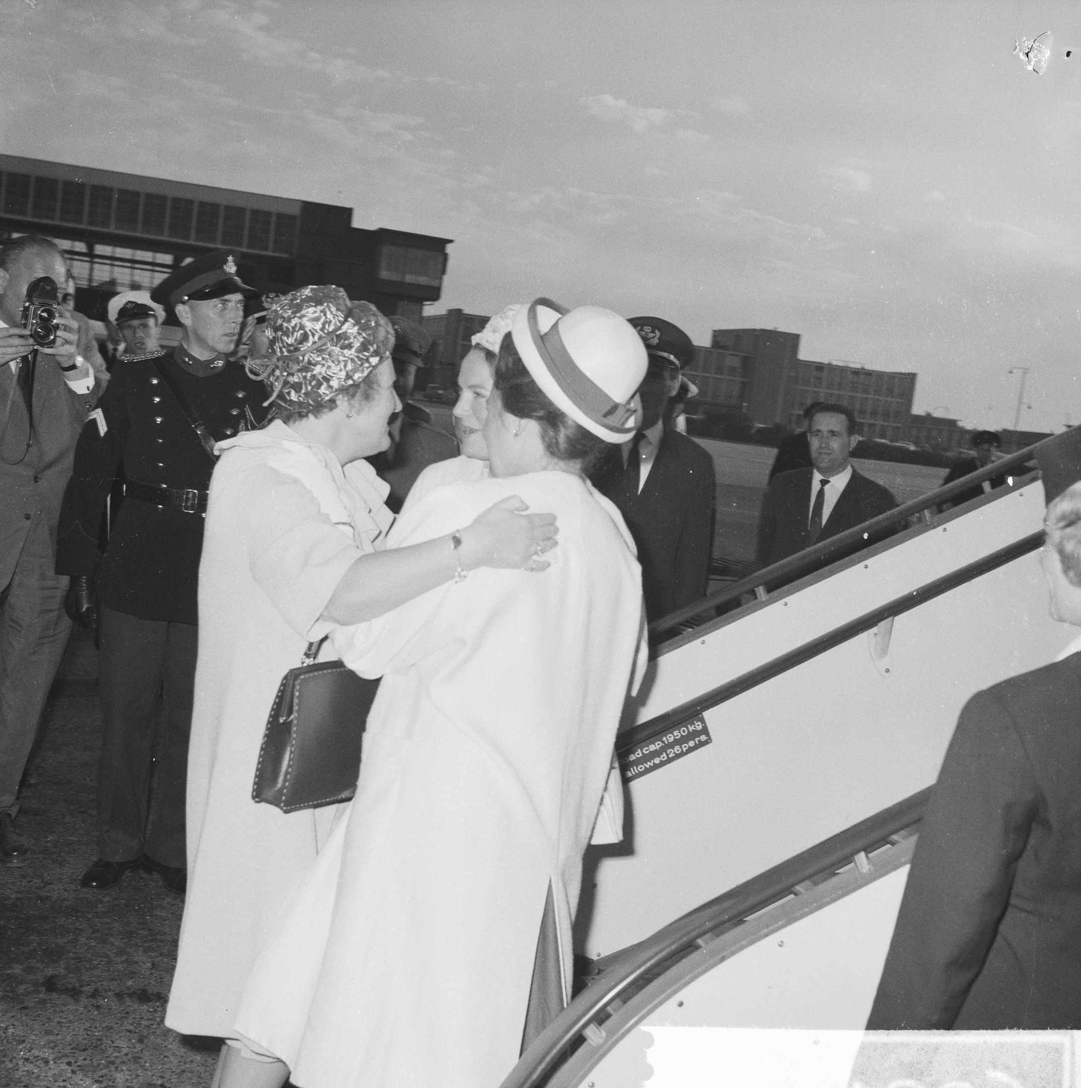 Königin Elizabeth II. und Prinz Philip, Herzog von Edinburgh, beim Ankunft am Heathrow Airport in London mit zwei Frauen, die sich umarmen, und einem Mann mit einer Kamera im Hintergrund.