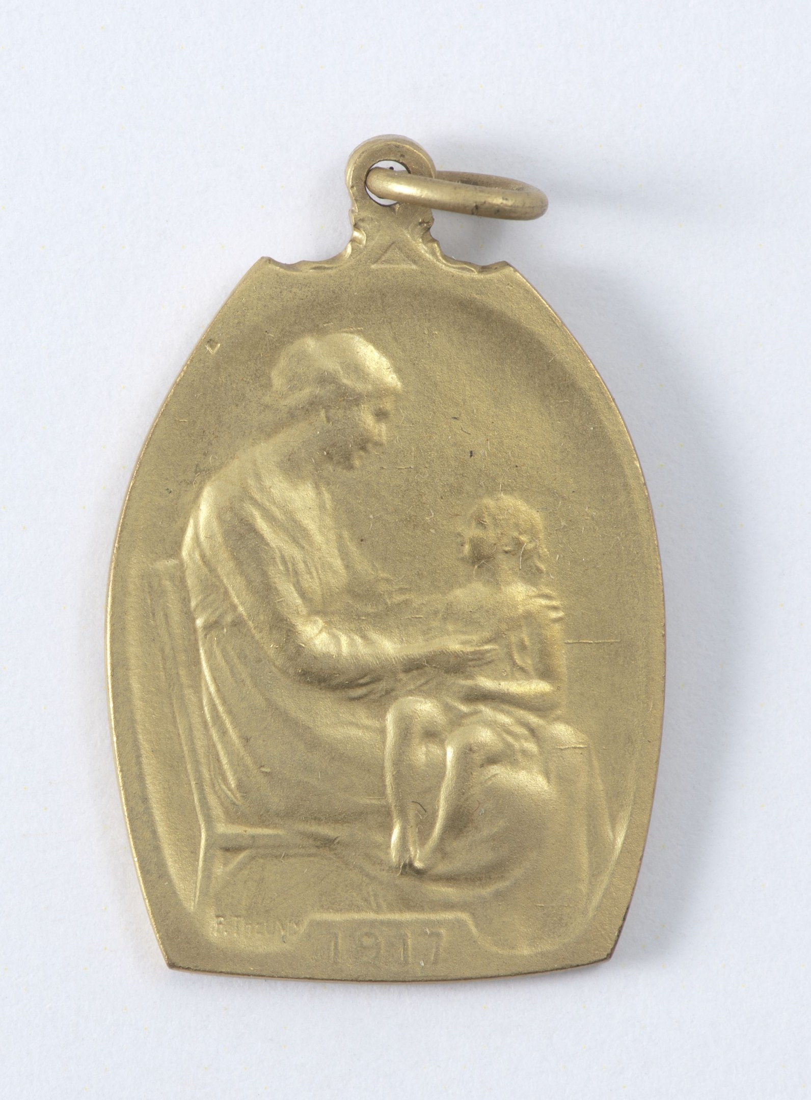 Goldmedaille mit Relief einer Frau in weißem Kleid mit Haarknoten, die ein Kind hält, beide sehen sich sanft an, beschriftet mit 'Mutter und Kind' in Kursivschrift.