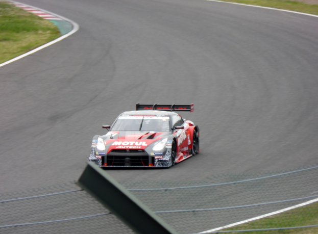 Ein Nissan GT-R Nismo GT3-Rennwagen auf der Nürburgring 24 Stunden-Rennstrecke, mit grünem Gras auf beiden Seiten der Strecke.