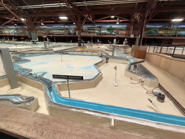Großes Indoor-Wasserpark mit mehreren Wasserbahnen, Deckenbeleuchtung, Wandgemälden und einem Minigolfplatz.
