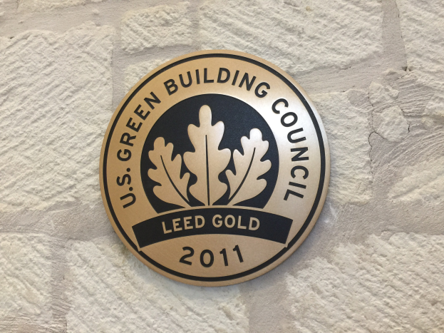 Logo der U.S. Green Building Council auf der Seite eines Gebäudes, mit einem grünen Schild mit weißer Umrandung, fetter schwarzer Schrift und einem umgebenden Lorbeerkranz.